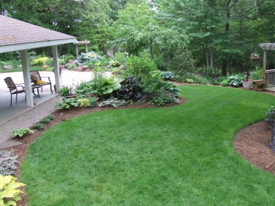 一个带露台、鲜花和修剪整齐的草坪的后院。gydF4y2Ba